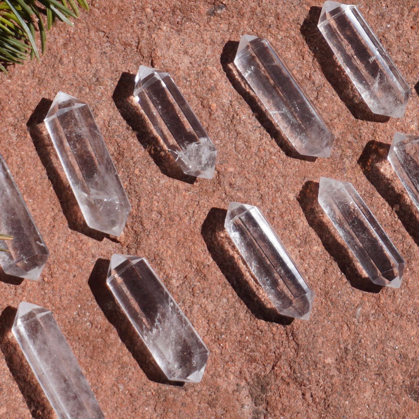 Grid of clear quartz double terminated points displayed on earthy terrain, ideal for manifestation rituals