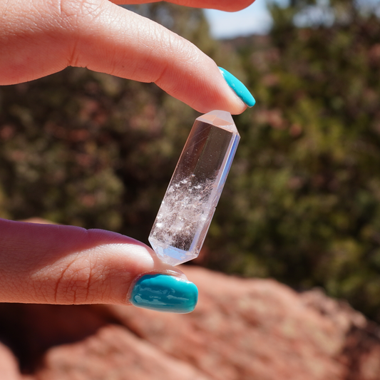Hand holding a clear quartz double terminated point outdoors, perfect for clarity and spiritual focus.