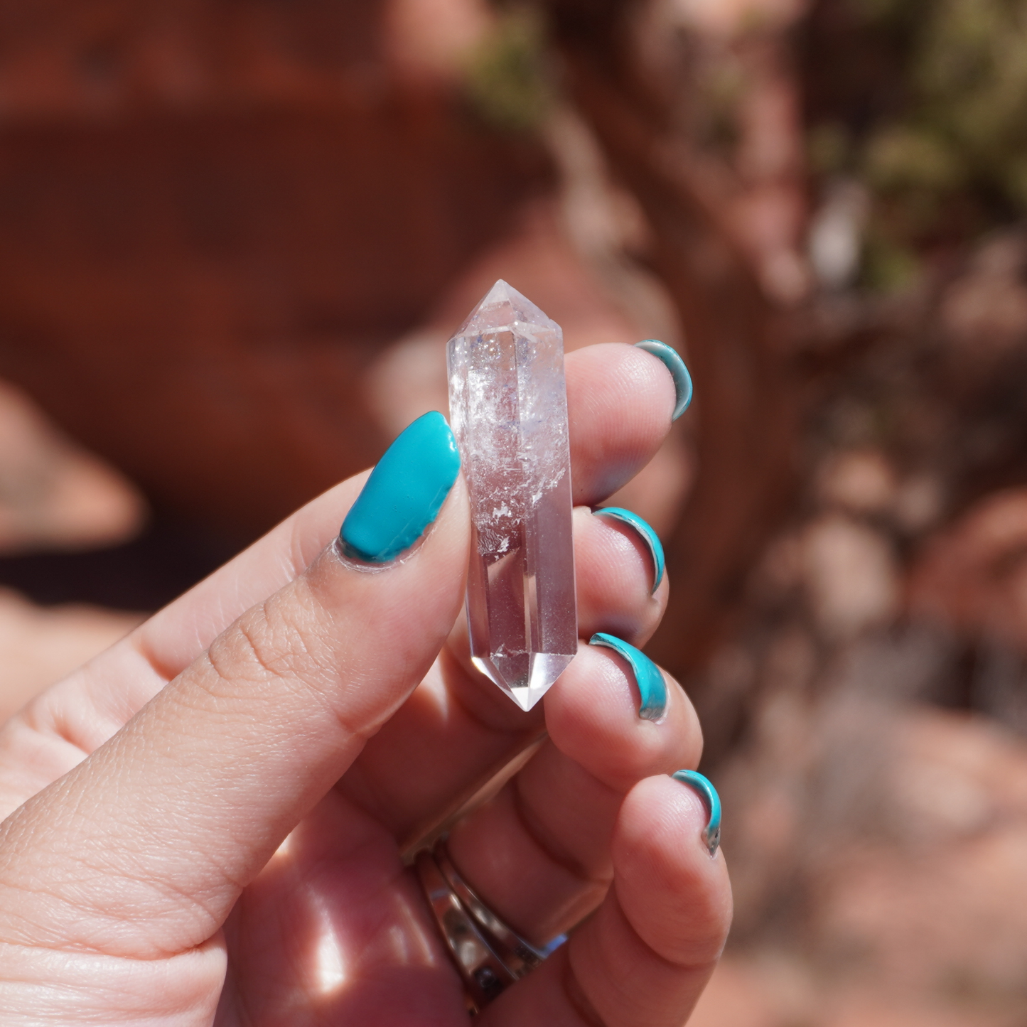 Hand showcasing a clear quartz point with natural inclusions, perfect for focused intention work
