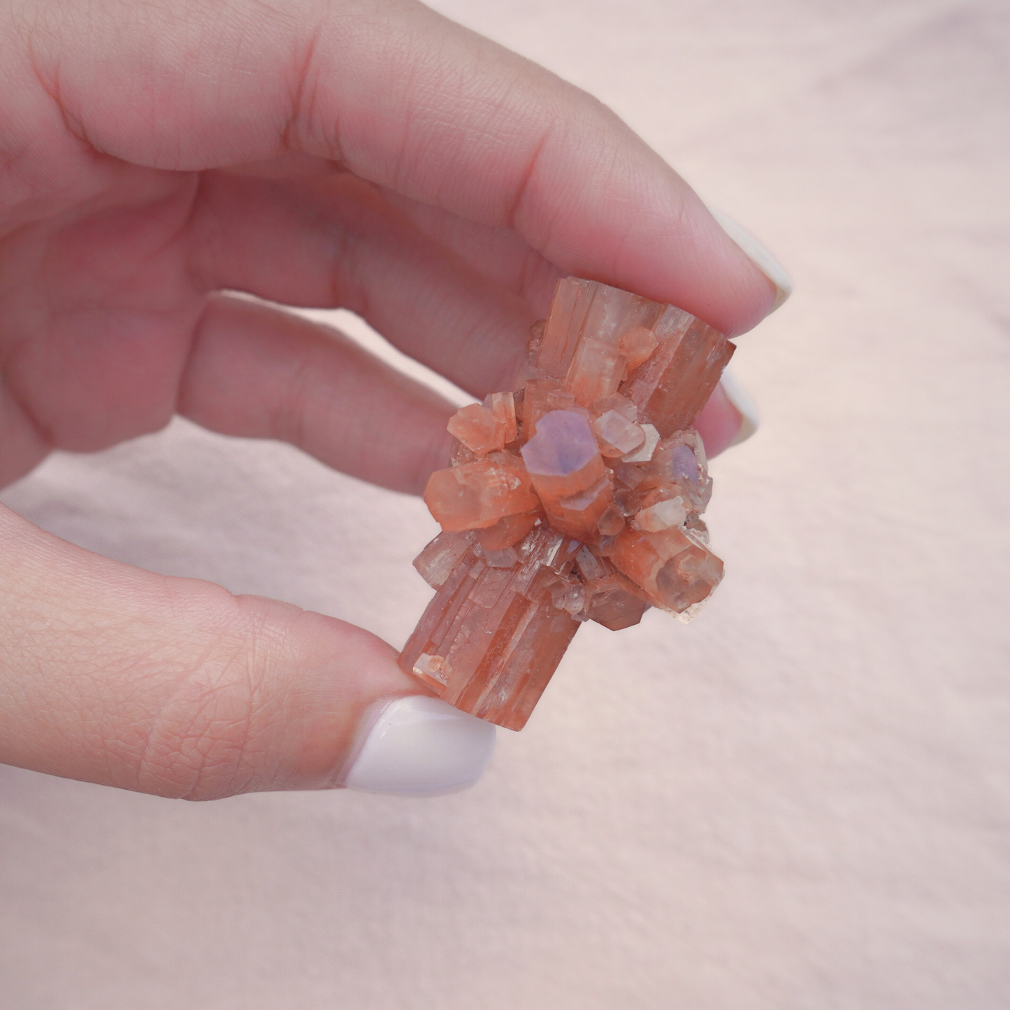 Delicate Raw Aragonite Crystal held between fingers, emphasizing its unique formation and metaphysical properties.