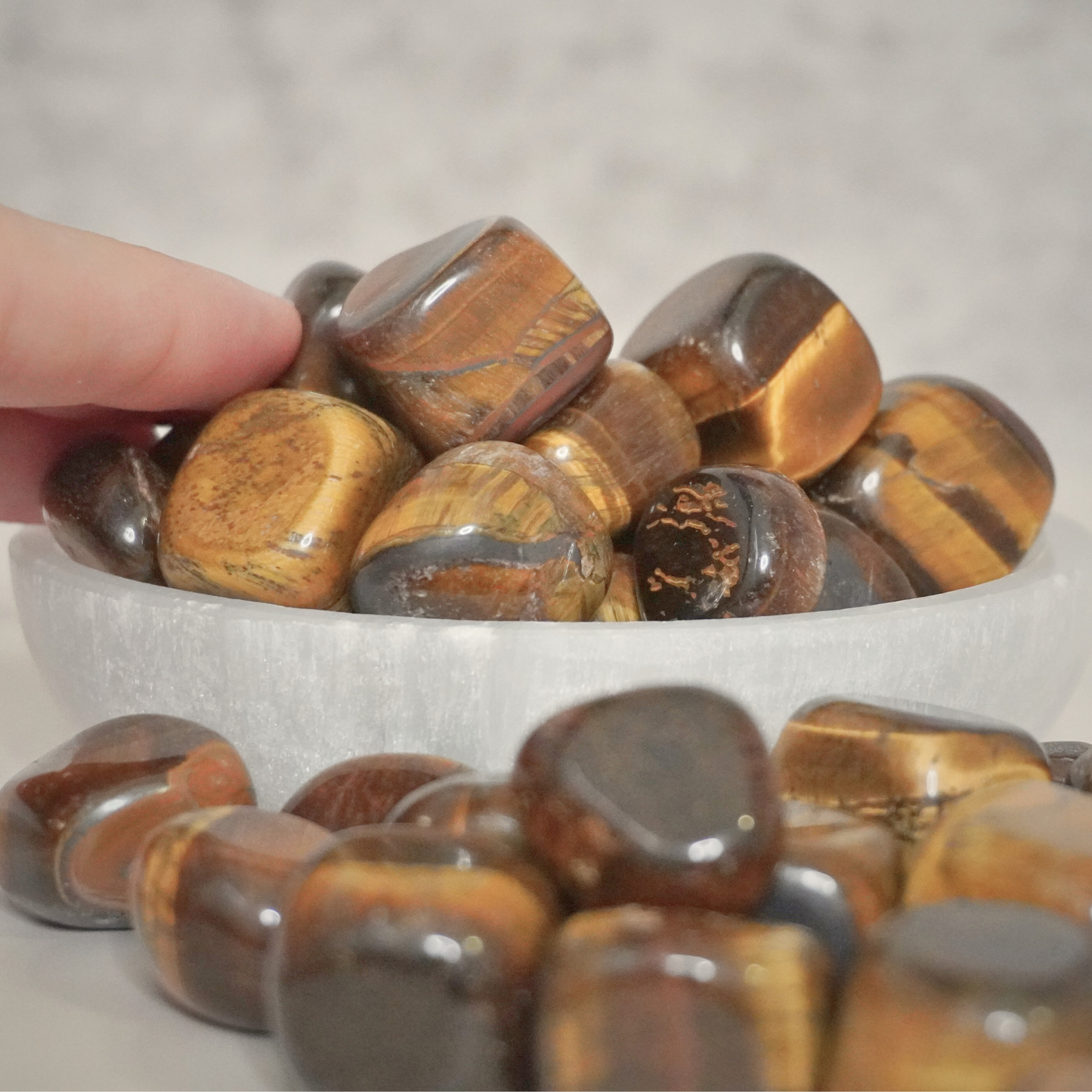 A close-up of polished Tiger's Eye tumbles scattered on a table, highlighting their protective and grounding qualities.