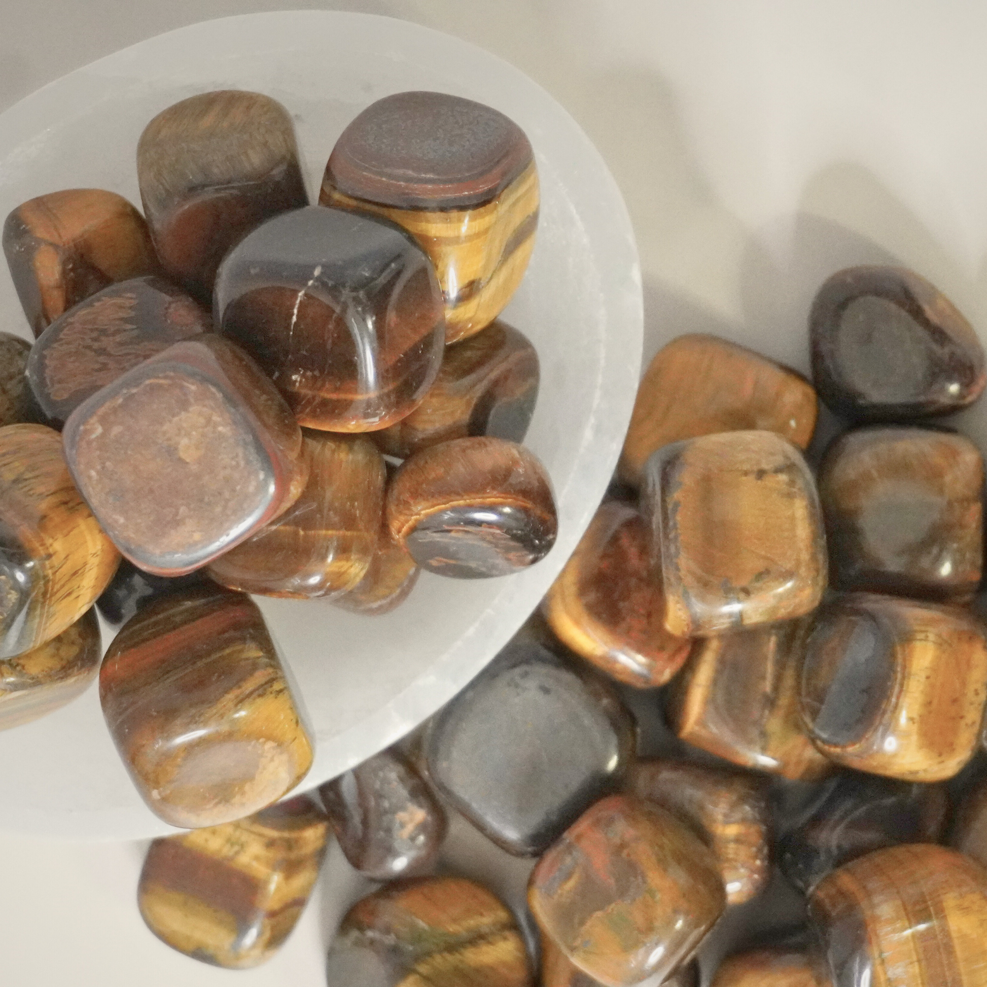 A bowl filled with Tiger's Eye tumbles, highlighting their earthy tones and protective qualities.