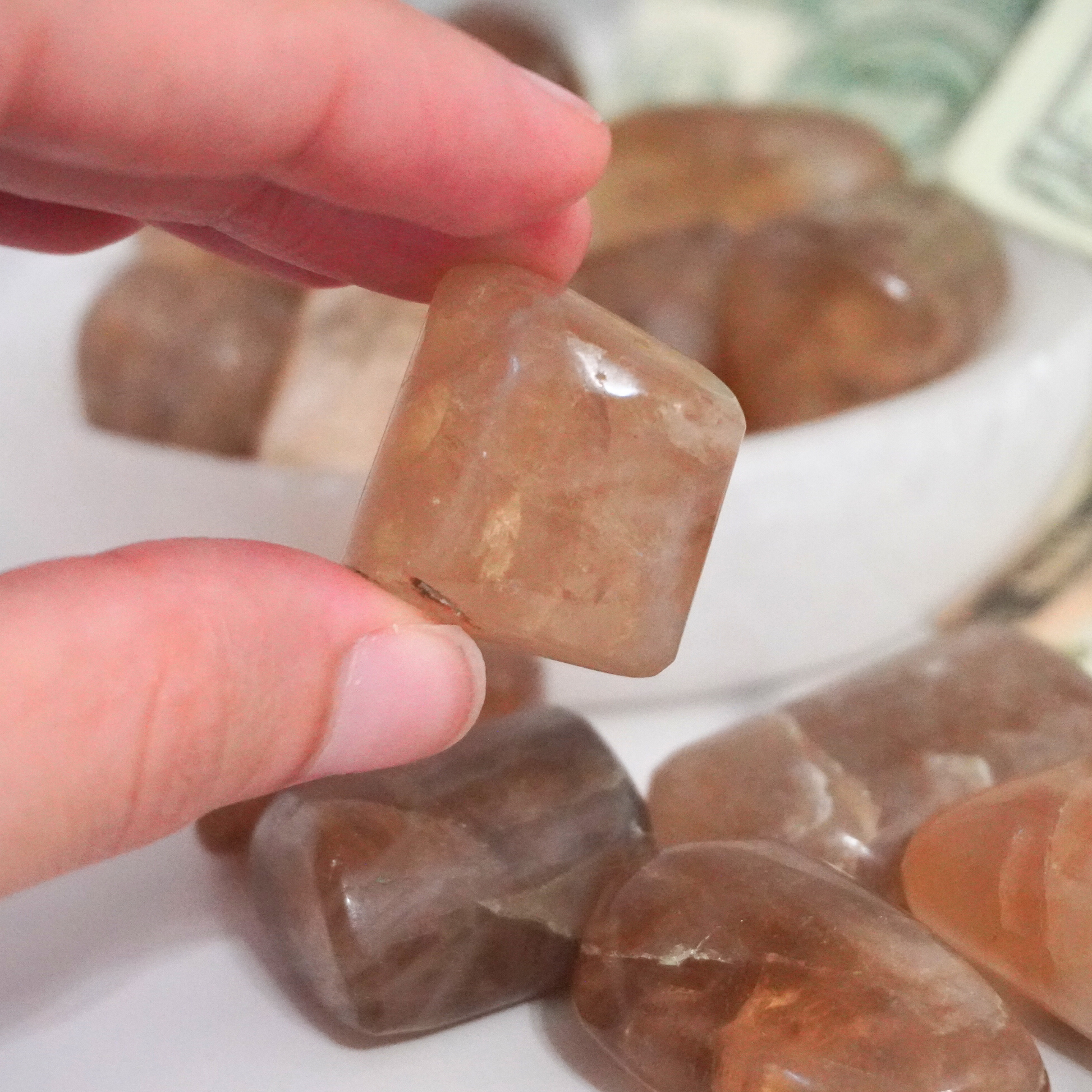 Smoky Citrine tumbles displayed in a bowl with money in the background