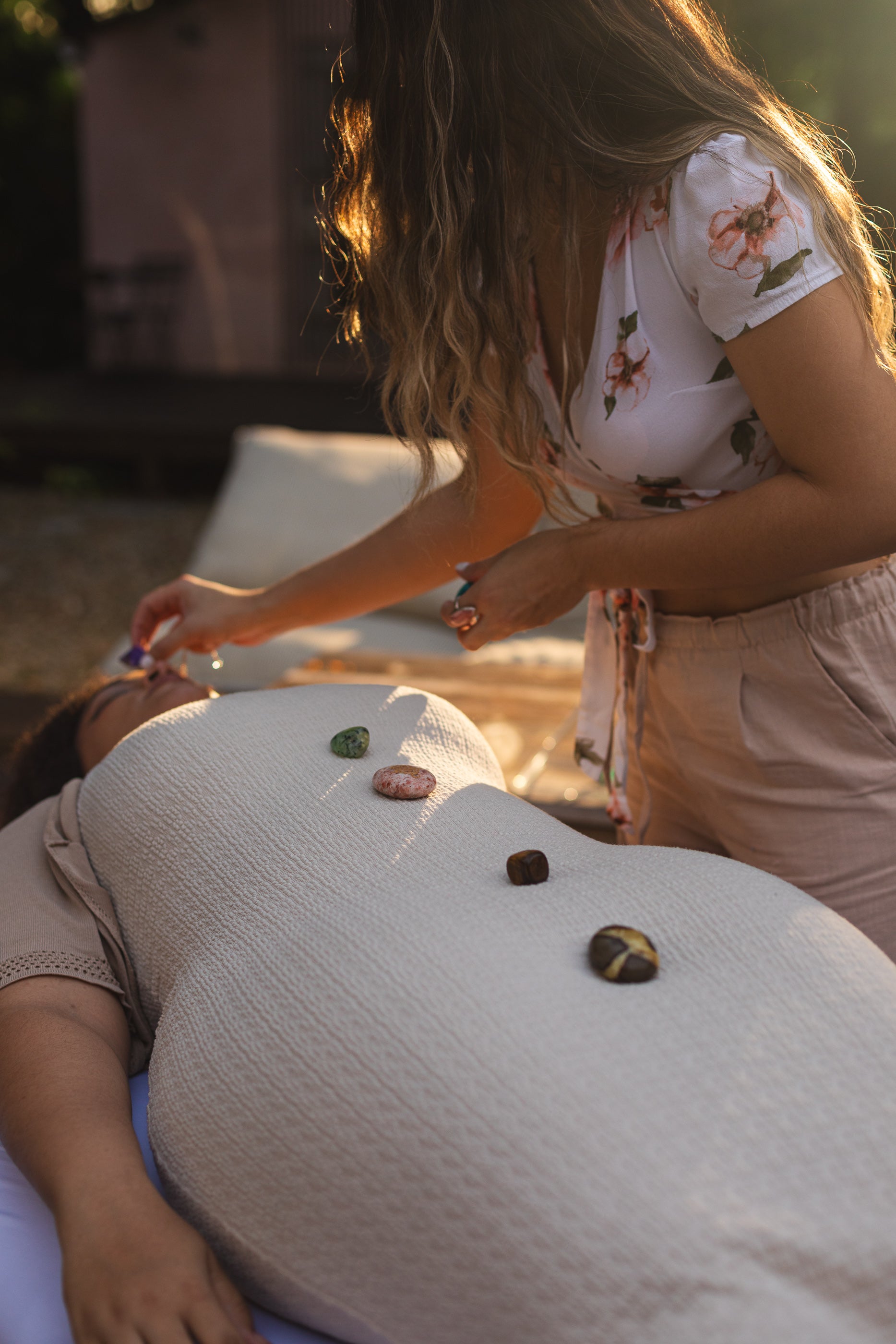 Sacred Owl Healers Certified healer performing an in-home Chakra Balancing session with healing crystals placed on the client’s body for energy alignment.