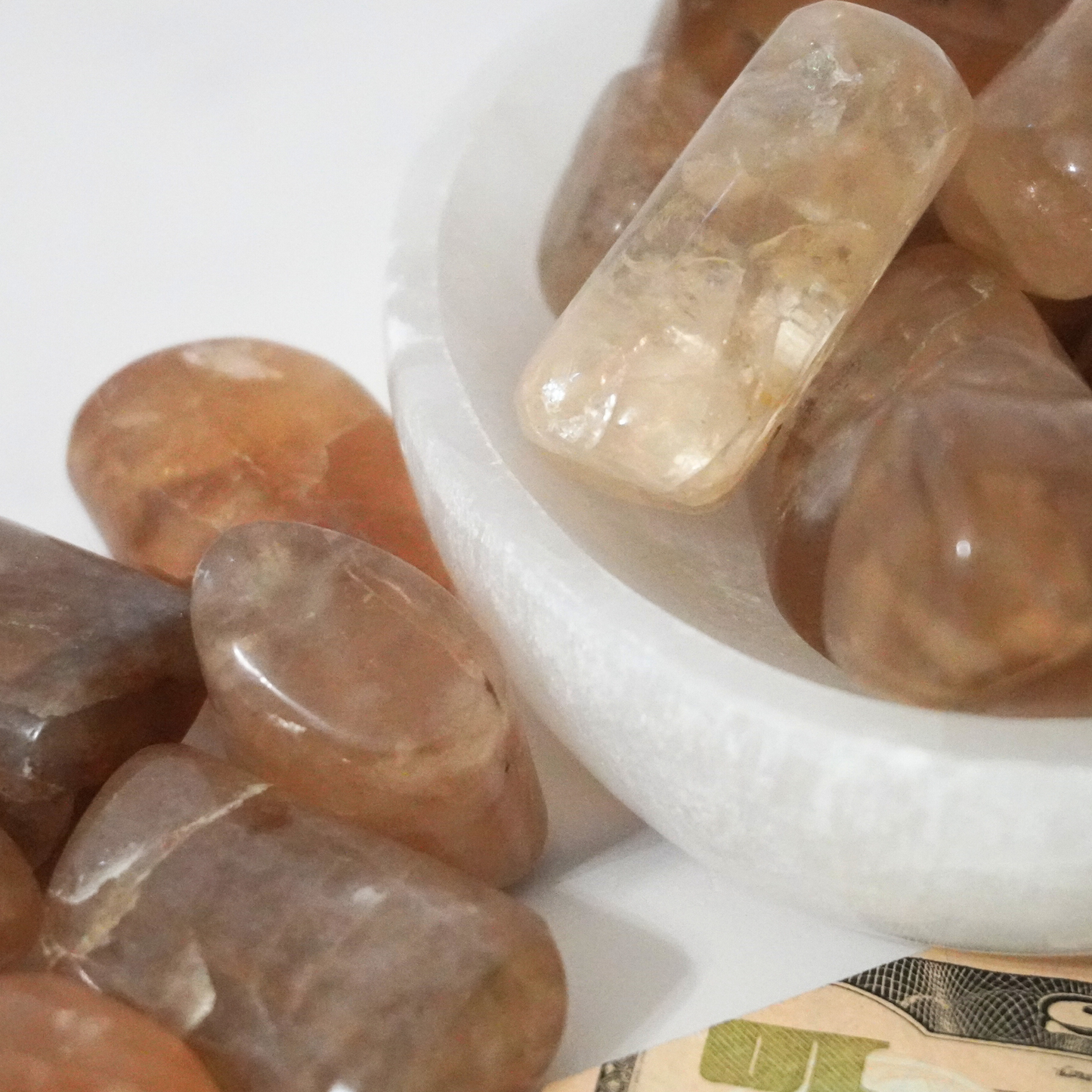 Smooth Smoky Citrine tumbles in a bowl with a focus on their reflective surfaces